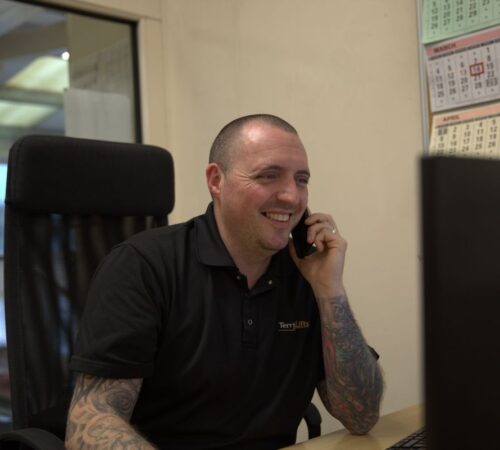 Picture of Terry Lifts installation and maintenance manager on the phone sitting at a desk.