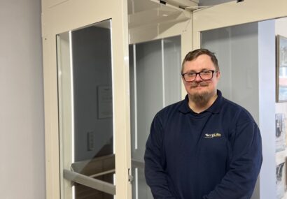 Terry Lifts CAD Technician stood in front of an affinity home lift model in the factory showroom.